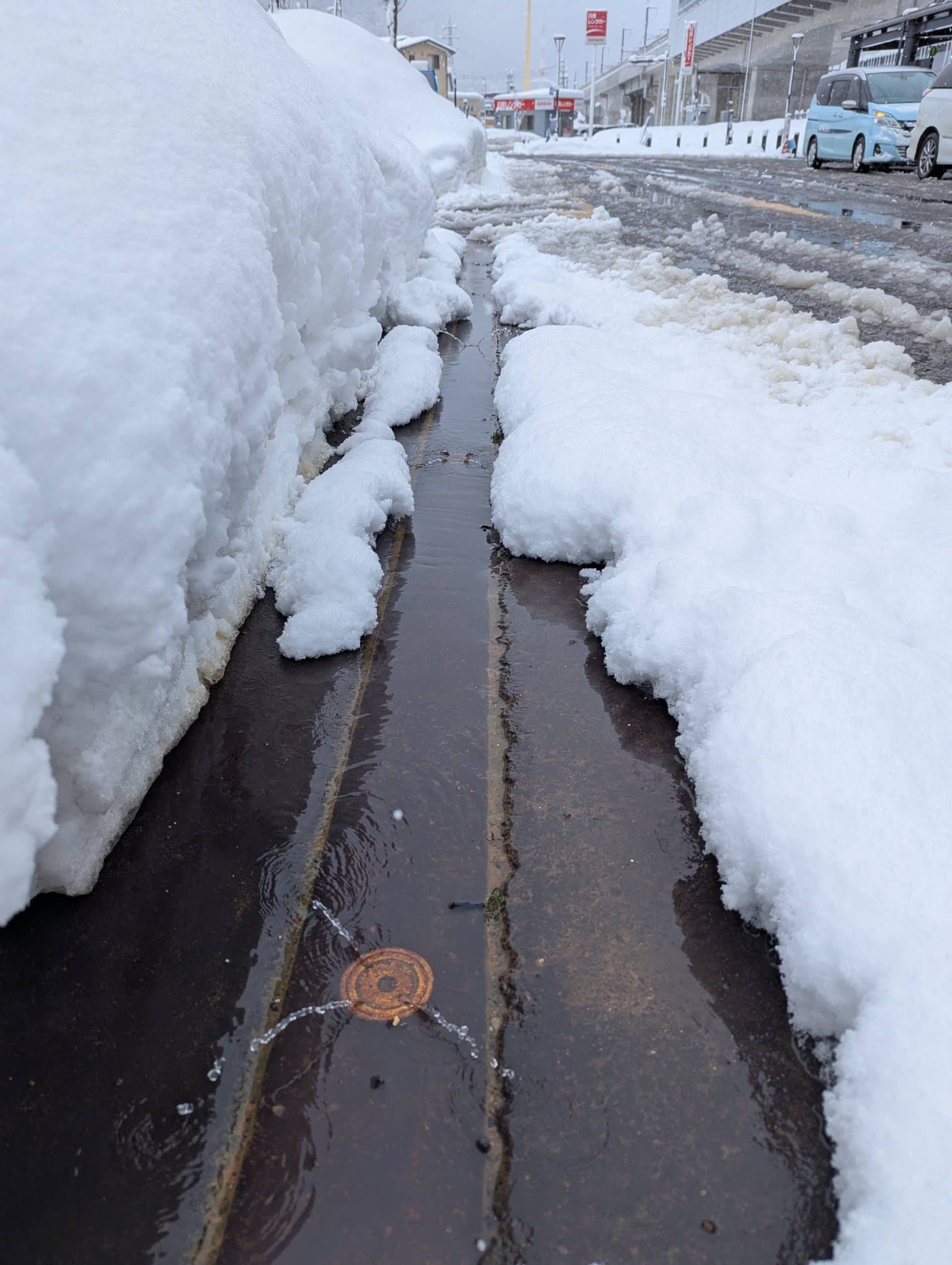 Water shooting out of small holes on the side of the road to melt snow