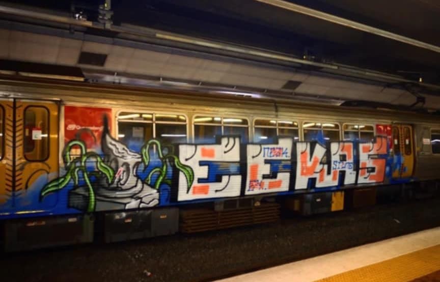 Another large colourful graffiti tag saying "Eekas" on the side of a train.
